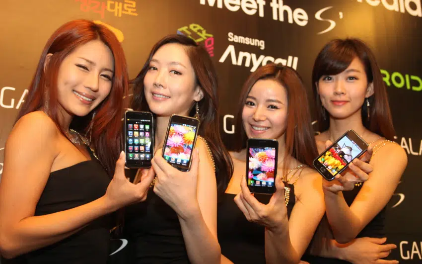trois femmes tenant leurs téléphones portables devant un mur
