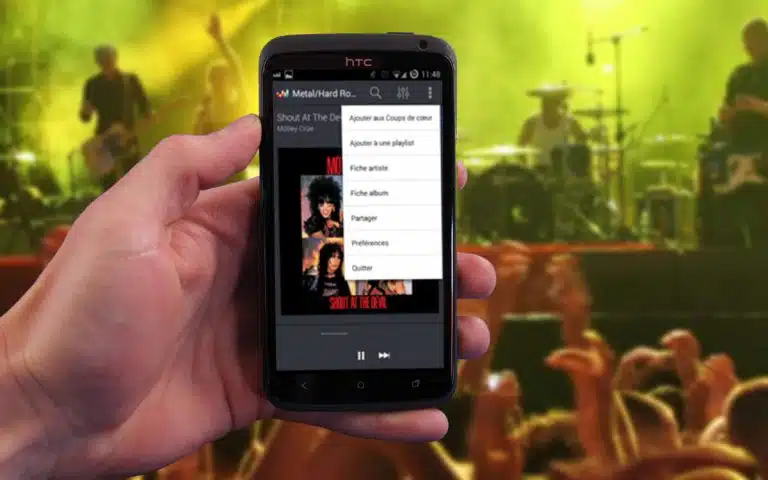 quelqu'un tenant un téléphone portable dans la main avec un concert en arrière-plan