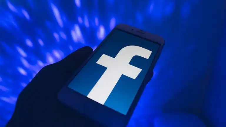 quelqu'un tenant un téléphone avec un logo facebook dessus